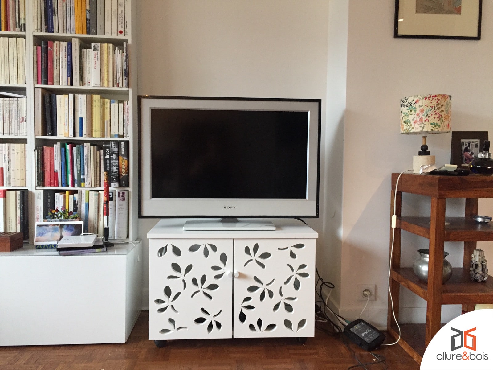 La console pour télévision avec ses portes battantes ajourées au motif floral.